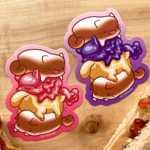 Op de afbeelding: Twee stickers met stapels van vier cartoonkatten, elk met een andere vulling. De katten zijn op elkaar gestapeld, waarbij de onderste kat de grootste is en de bovenste kat de kleinste. De stickers bevinden zich op een houten oppervlak. De tekst "@CTKRStudio" staat op elke sticker.