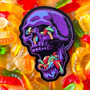 May include: Purple skull sticker with a black background. The skull's eyes and mouth are filled with colorful gummy worms. The sticker has the text "&copy;2021 CTR Studio" in the lower right corner.