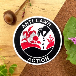 May include: A black and white round sticker with the words "Anti Lawn Action" in white lettering. The sticker features a red and white illustration of a hand planting seeds in the ground.