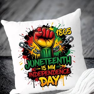 May include: White square pillow with a colorful graphic design. The design features a clenched fist in red, yellow, and green, with broken chains and the text "Juneteenth is my Independence Day" and the year "1865".