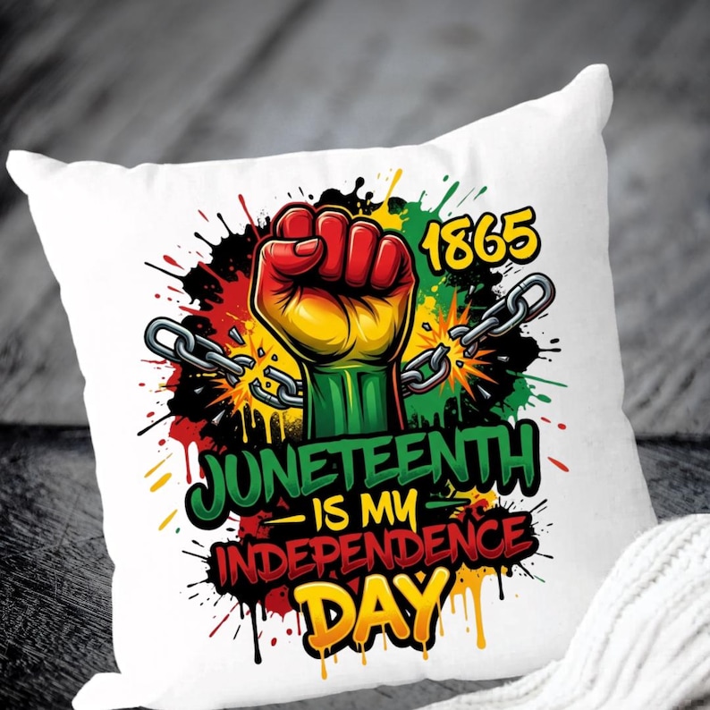 May include: White square pillow with a colorful graphic design. The design features a clenched fist in red, yellow, and green, with broken chains and the text "Juneteenth is my Independence Day" and the year "1865".