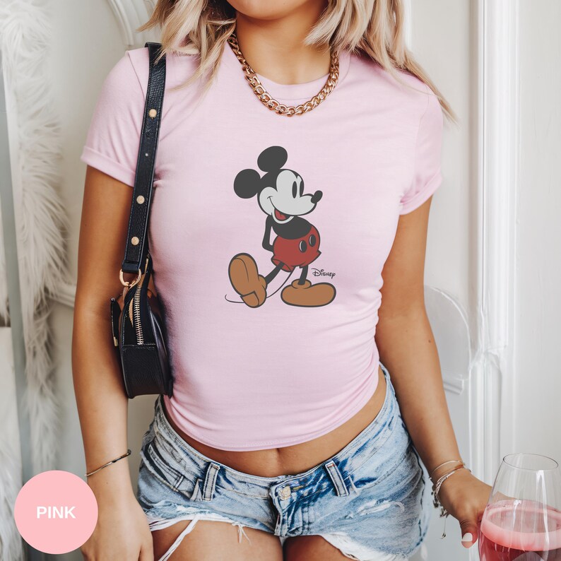 Puede incluir: Camiseta rosa claro con un dise&ntilde;o de Mickey Mouse. El personaje de dibujos animados es de color negro, rojo y marr&oacute;n, con el logotipo de Disney. La camiseta tiene mangas cortas y cuello redondo.