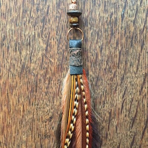 May include: A pair of long, brown, orange, and black feather earrings with a leather and bead accent.