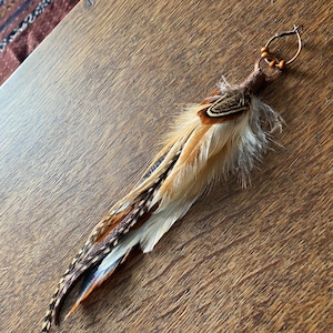 May include: A brown and white feather earring with a brown wooden bead and a copper wire hoop.