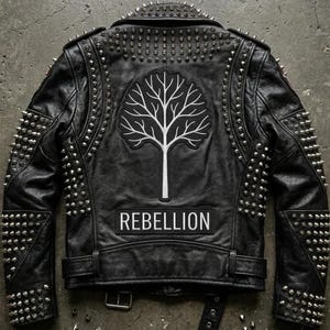 May include: Black leather jacket with silver studs and spikes. A white tree patch is centered on the back, above a rectangular patch that reads "REBELLION". The jacket has a buckle belt at the waist.