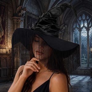 May include: A black witch hat featuring a tall, pointed, ruched crown and a wide, flat brim. The entire edge of the brim is adorned with long, thin, black fringe that hangs down to cover the upper portion of the face in a veil-like effect.