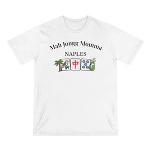 May include: A white short-sleeve t-shirt featuring the black text Mah Jongg Momma and NAPLES above a graphic of three mahjong tiles, a palm tree, and a golf bag. The tiles display a bird, a red Chinese character, and five blue circles.