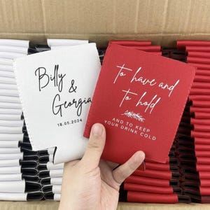 May include: A white foam can cooler printed with the black text Billy & Georgia 18.05.2024 and a red foam can cooler printed with the white text To have and to hold AND TO KEEP YOUR DRINK COLD with a small leaf graphic in a cardboard box.