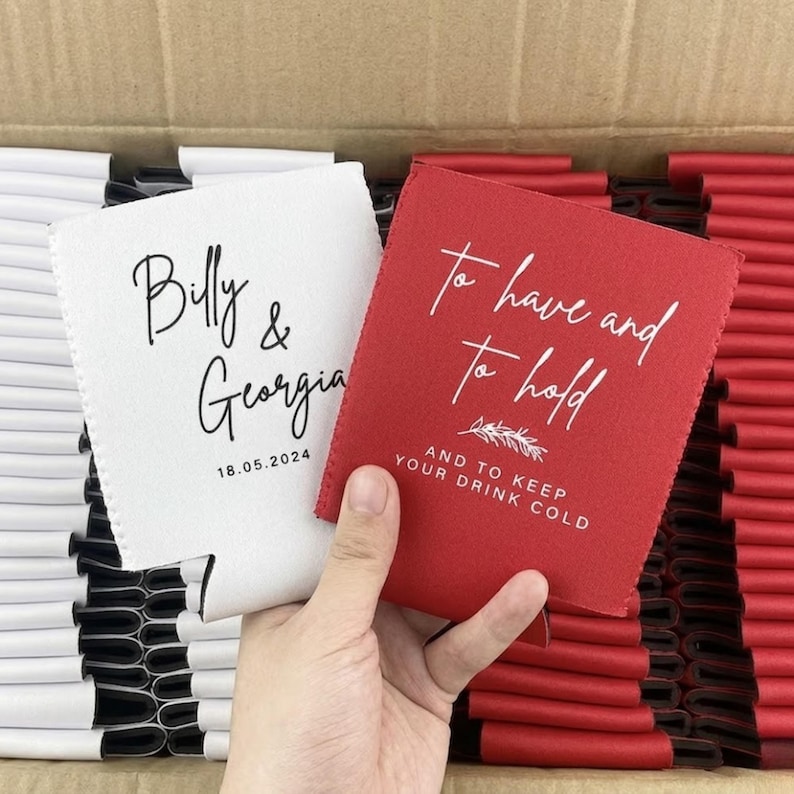 May include: A white foam can cooler printed with the black text Billy & Georgia 18.05.2024 and a red foam can cooler printed with the white text To have and to hold AND TO KEEP YOUR DRINK COLD with a small leaf graphic in a cardboard box.