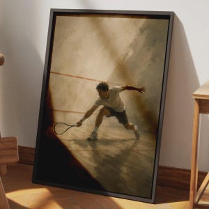 May include: A framed wall art print depicting a squash player in a lunge position, wearing a white t-shirt and dark shorts, holding a racket on a court with red lines. The scene features warm, muted tones and dramatic shadows in a vertical orientation.