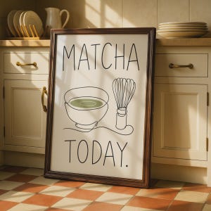 May include: A framed wall art print featuring a minimalist black line drawing of a matcha bowl and a bamboo whisk. The text MATCHA TODAY is printed in black capital letters. The background is off-white, and the frame is a dark brown wood.