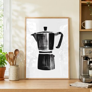 May include: A framed black and white print of a stovetop espresso maker. The artwork is a minimalist brushstroke style. The image is a kitchen-themed art piece, suitable for coffee enthusiasts.