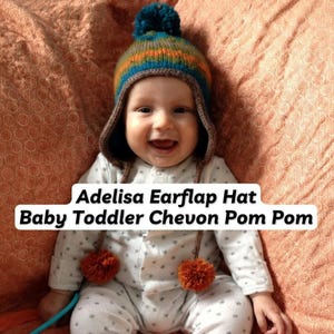Puede incluir: Un bebé sonriente con un gorro de orejeras de punto colorido con un pompón en la parte superior y dos pompones en las orejeras. El gorro tiene rayas azules, naranjas y verdes. El texto de la imagen dice: Adelisa Earflap Hat Baby Toddler Chevon Pom Pom.