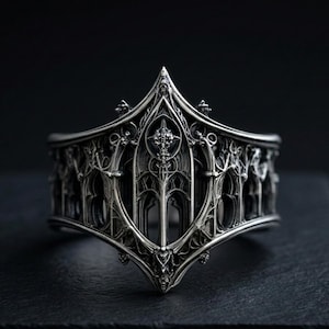 May include: A detailed silver-colored ring with an intricate gothic architectural design. The ring features arched windows, spires, and a central cross motif. The band is wide, with a textured, ornate surface, and is set against a dark background.