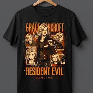 May include: Black t-shirt featuring a graphic of a woman with blonde hair, holding a gun, with the text "GRACE CROFT" and "RESIDENT EVIL requiem". The design includes multiple images of the woman and the phrase "RACCOON CITY NEVER FORGETS".