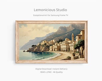 May include: A framed digital art print depicting a coastal town with buildings, a beach, and mountains. The artwork is in a watercolor style, with soft colours and a tranquil atmosphere. The frame is light-coloured wood. Text on the image reads "Lemonicious Studio" and "Exceptional Art For Samsung Frame TV."