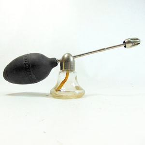 May include: A vintage glass perfume atomizer with a black rubber bulb and a silver metal nozzle. The atomizer has a bell-shaped base.