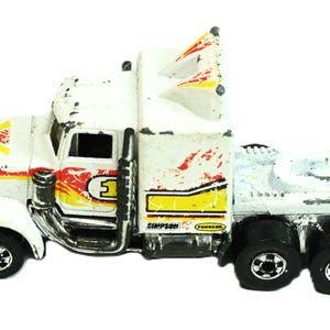 May include: A white toy semi-truck with red and yellow flame graphics on the hood and sides. The truck features a black exhaust pipe, black wheels, and the number 1 printed on the side. The text Simpson and Pennzoil are visible on the side.