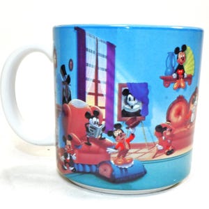 Puede incluir: Una taza de cer&aacute;mica azul con asa blanca presenta una ilustraci&oacute;n de dibujos animados de Mickey Mouse y sus amigos en un ambiente de habitaci&oacute;n. La taza tiene un fondo azul con una ventana, un marco de imagen y un sill&oacute;n rojo.