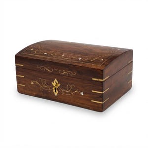 May include: A rectangular dark brown wooden box with a curved lid, featuring brass corner inlays and delicate brass wire scrollwork patterns. The front includes a central brass keyhole escutcheon with a small brass key inserted inside.