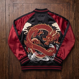Può includere: Un giubbotto bomber in raso nero e bordeaux con un grande ricamo dettagliato di un drago rosso sul retro. Il design include nuvole ricamate bianche e onde stilizzate sul fondo. Il giubbotto presenta colletto, polsini e orlo a coste.