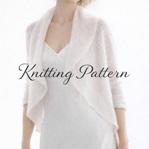 Op de afbeelding: Een zachte, witte gebreide sjaal met een gedrapeerd ontwerp. De sjaal wordt over een witte jurk gedragen. De woorden "Knitting Pattern" staan cursief over de afbeelding.