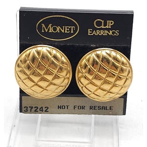 May include: A white ceramic mug with a black handle and the text "But First, Coffee" in a bold, black font. The mug is set against a blurred background, suggesting a cosy setting.