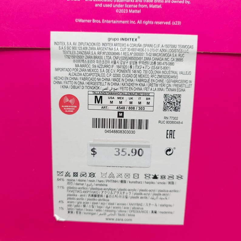 K&ouml;nnte beinhalten: Ein Zara-Produktetikett mit der Gr&ouml;&szlig;e 'M' und einem Preis von 35,90 $. Das Etikett enth&auml;lt Angaben zu Materialien wie Harz und Kunststoff-Acryl sowie internationale Herstellungsinformationen.