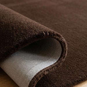 Full overhead view of this solid brown area rug, an authentic hand-tufted premium Wollteppich featuring a rich chocolate tone and dense plush texture.