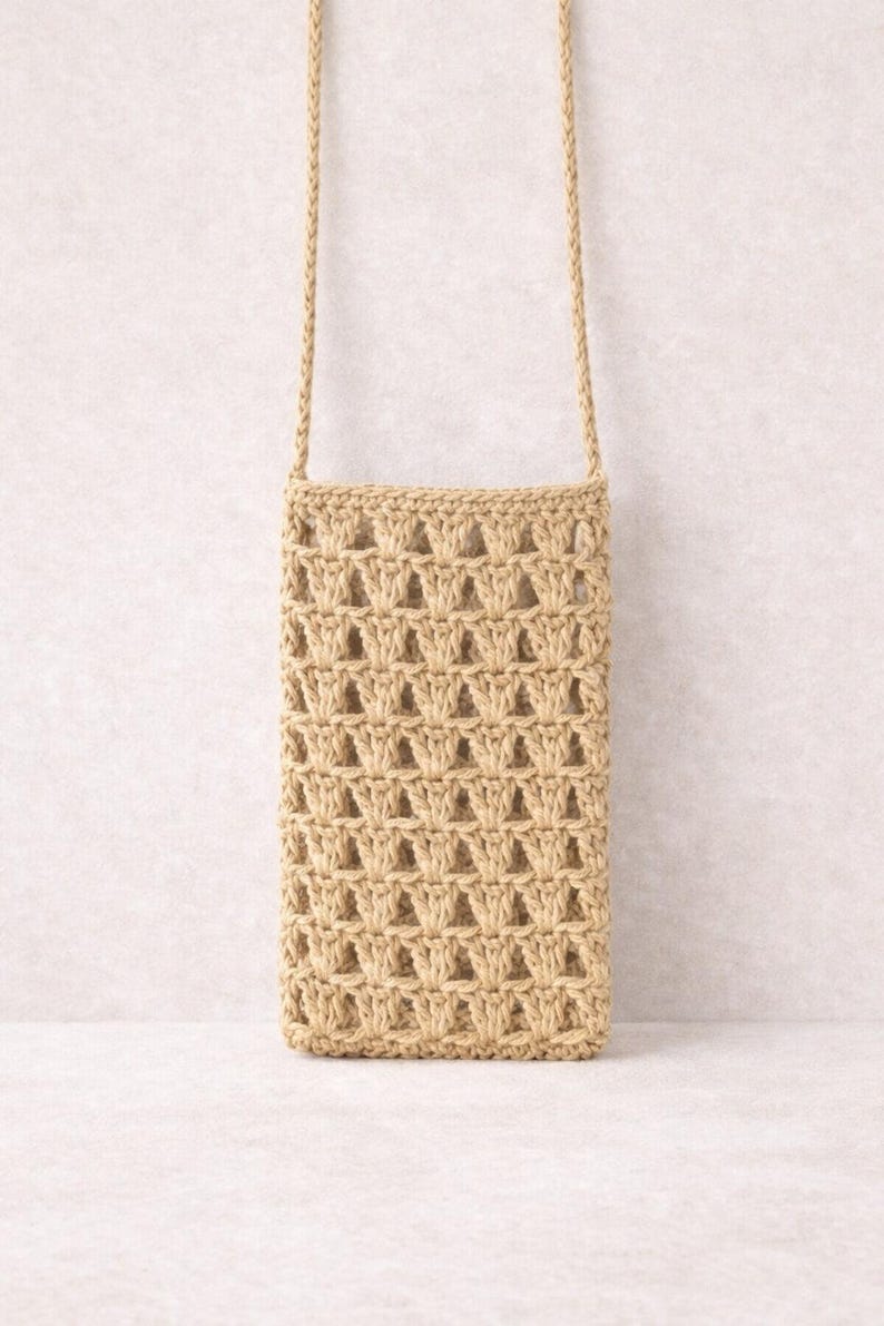 Pu&ograve; includere: Una borsa a tracolla beige all'uncinetto con un motivo intrecciato. La borsa ha una forma rettangolare e una lunga tracolla intrecciata. La borsa &egrave; realizzata con un filato color naturale ed &egrave; progettata per contenere un telefono o piccoli oggetti.