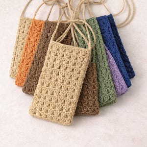 Pu&ograve; includere: Una collezione di sette custodie per telefono all'uncinetto in vari colori, tra cui beige, arancione, marrone, verde, blu e viola. Ogni custodia ha un cinturino intrecciato abbinato per il trasporto. Le custodie sono in materiale.
