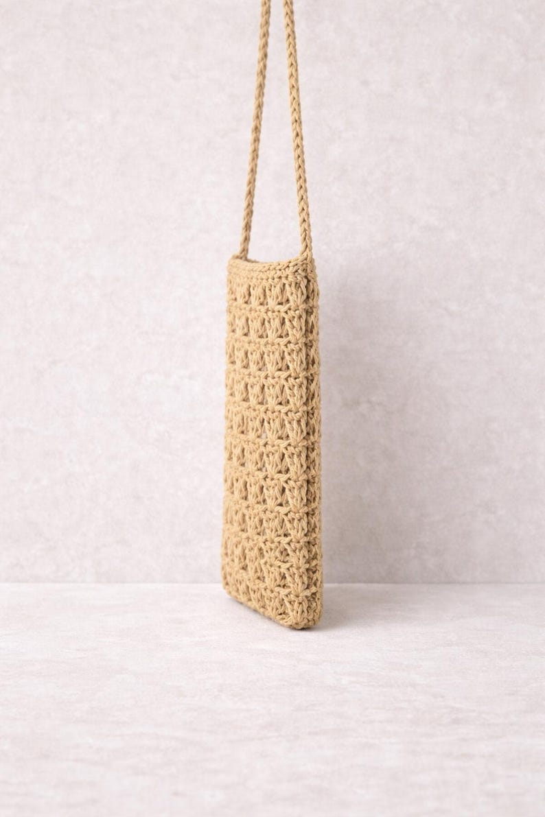 Pu&ograve; includere: Una borsa rettangolare beige all'uncinetto con una lunga tracolla intrecciata. La borsa presenta un motivo a trama aperta e strutturata. La tracolla &egrave; attaccata in alto, permettendo di indossarla a spalla o a tracolla. La borsa &egrave; vuota.