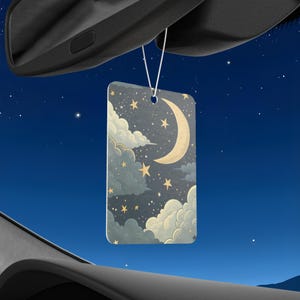Puede incluir: Ambientador rectangular para coche con diseño de cielo nocturno. La imagen presenta una luna creciente, estrellas y nubes en tonos amarillos, grises y azules. El ambientador está colgado de una cuerda blanca.