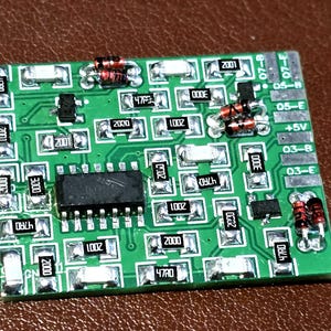 May include: A green circuit board with various electronic components, including resistors, capacitors, and an integrated circuit. The board has several labels and markings, including "2001" and "4780".