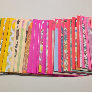 May include: A collection of colorful handmade envelopes in various patterns and colors, including purple, blue, green, yellow, pink, and patterned designs. The envelopes are arranged in a fan shape, showcasing their diverse designs.