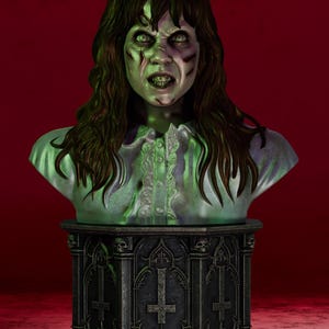 Puede incluir: Un busto de una persona con cabello largo y oscuro, piel pálida con tonos verdosos y una expresión facial angustiada. La figura viste una camisa de cuello claro y está montada sobre un pedestal oscuro y ornamentado con cruces y calaveras talladas.