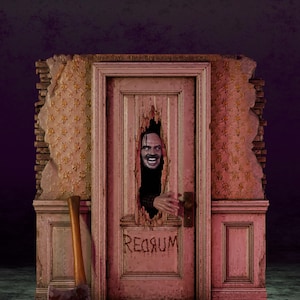 Op de afbeelding: Een 3D-diorama met een roze deur met een grillig gat, waar een grijnzend gezicht doorheen kijkt. Op de deur staat de tekst REDRUM in donkere letters. Een bijl rust op de basis, die is gelabeld met NOSTALGIAHORROR3D. De muur eromheen heeft een bloemenbehang.