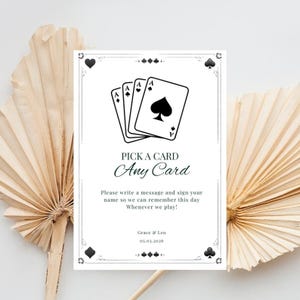 May include: A white card with a black border and playing card illustrations. The text reads "PICK A CARD Any Card" with a request to sign a message. The date "05.03.2026" is also included.