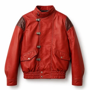 May include: A bright red leather jacket featuring dark brown shoulder panels, a high collar with a buckle strap, and a front closure with four metal clasps. The jacket includes two flap pockets with silver snaps and a ribbed elastic waistband.