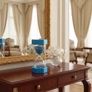 May include: An hourglass with a bright blue hexagonal frame and clear glass chambers containing blue sand. The hourglass is positioned upright, showing the sand flowing from the top bulb into the bottom bulb, creating a distinct hourglass shape.