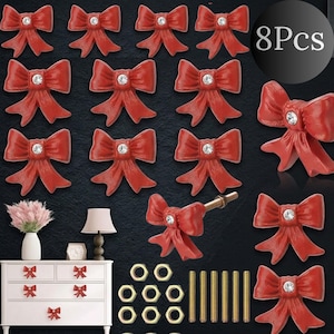 May include: Red bow-shaped cabinet knobs with a sparkling rhinestone center. The image shows multiple knobs, hardware, and a white cabinet with matching bow knobs. The text "8Pcs" is visible in the image.