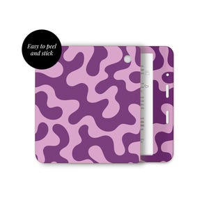 May include: A case with a purple and light purple abstract pattern, with a white interior. The case is open, showing a white object with text. The text on the black circle says "Easy to peel and stick."