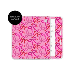 Pode incluir: Uma capa de tablet rosa com um padrão repetido de laços rosa e vermelhos. A capa está aberta, revelando um interior branco com texto. Um círculo preto com o texto "Easy to peel and stick" está no canto superior esquerdo.