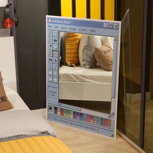 Puede incluir: Un espejo rectangular grande dise&ntilde;ado para parecerse a la interfaz cl&aacute;sica "untitled-Paint". El marco del espejo es blanco, con un dise&ntilde;o de interfaz azul y gris. El reflejo muestra una cama con almohadas. El texto "untitled-Paint" es visible en la parte superior.