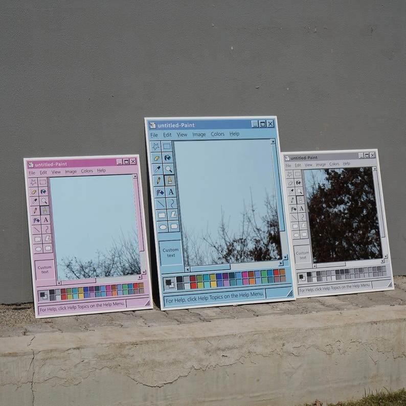Puede incluir: Tres espejos dise&ntilde;ados para parecerse a la ventana de la aplicaci&oacute;n "untitled-Paint". Los espejos son de color rosa, azul y gris, con una barra de herramientas y una paleta de colores. El texto "untitled-Paint" y otras opciones de men&uacute; son visibles. Los espejos reflejan el cielo y los &aacute;rboles.