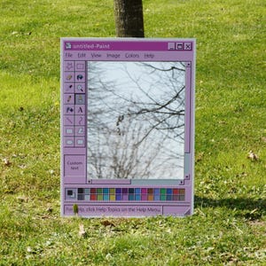 Puede incluir: Espejo rectangular con marco rosa que simula una ventana de Paint de Windows. Refleja un &aacute;rbol contra un cielo azul. El texto "untitled-Paint" est&aacute; en la parte superior, con una barra de men&uacute; y una paleta de colores en la parte inferior.