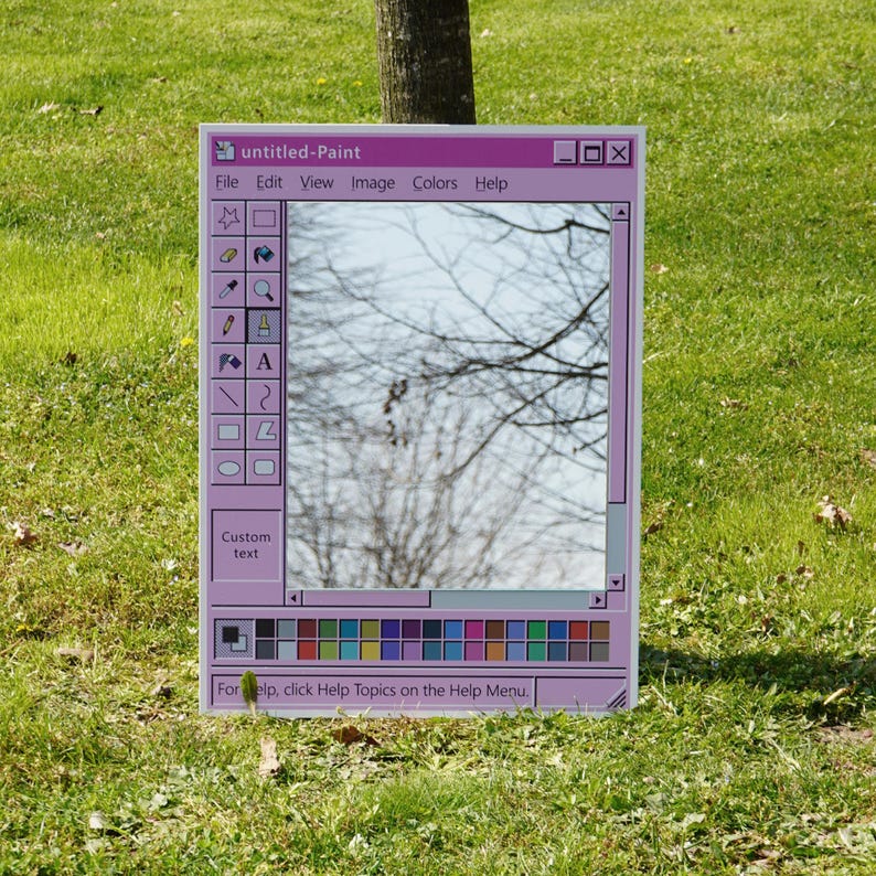 Puede incluir: Espejo rectangular con marco rosa que simula una ventana de Paint de Windows. Refleja un &aacute;rbol contra un cielo azul. El texto "untitled-Paint" est&aacute; en la parte superior, con una barra de men&uacute; y una paleta de colores en la parte inferior.