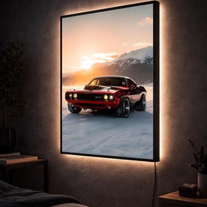 Puede incluir: Arte mural enmarcado con un coche deportivo rojo y negro sobre un paisaje nevado con montañas y una puesta de sol. La obra de arte está iluminada por un marco cálido y brillante, creando un efecto dramático. El coche es el punto focal.