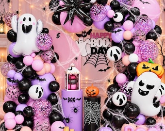 May include: A Halloween balloon arch kit featuring black, purple, and pink balloons, white ghost-shaped foil balloons, orange pumpkin balloons, and confetti-filled balloons. Includes a sign reading Happy Boo Day, a lantern, and spider web decor.