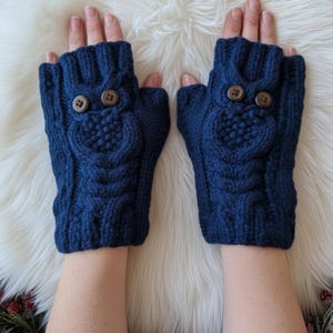 May include: A pair of dark blue fingerless gloves featuring a textured cable knit pattern and two brown buttons on each glove that resemble owl eyes. The gloves have a ribbed cuff at the wrist and an open design for the fingers and thumb.